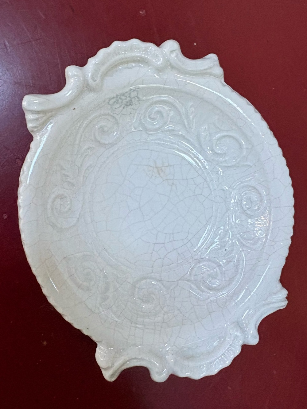Vintage ceramic dish with a white glaze and intricate scalloped edges.